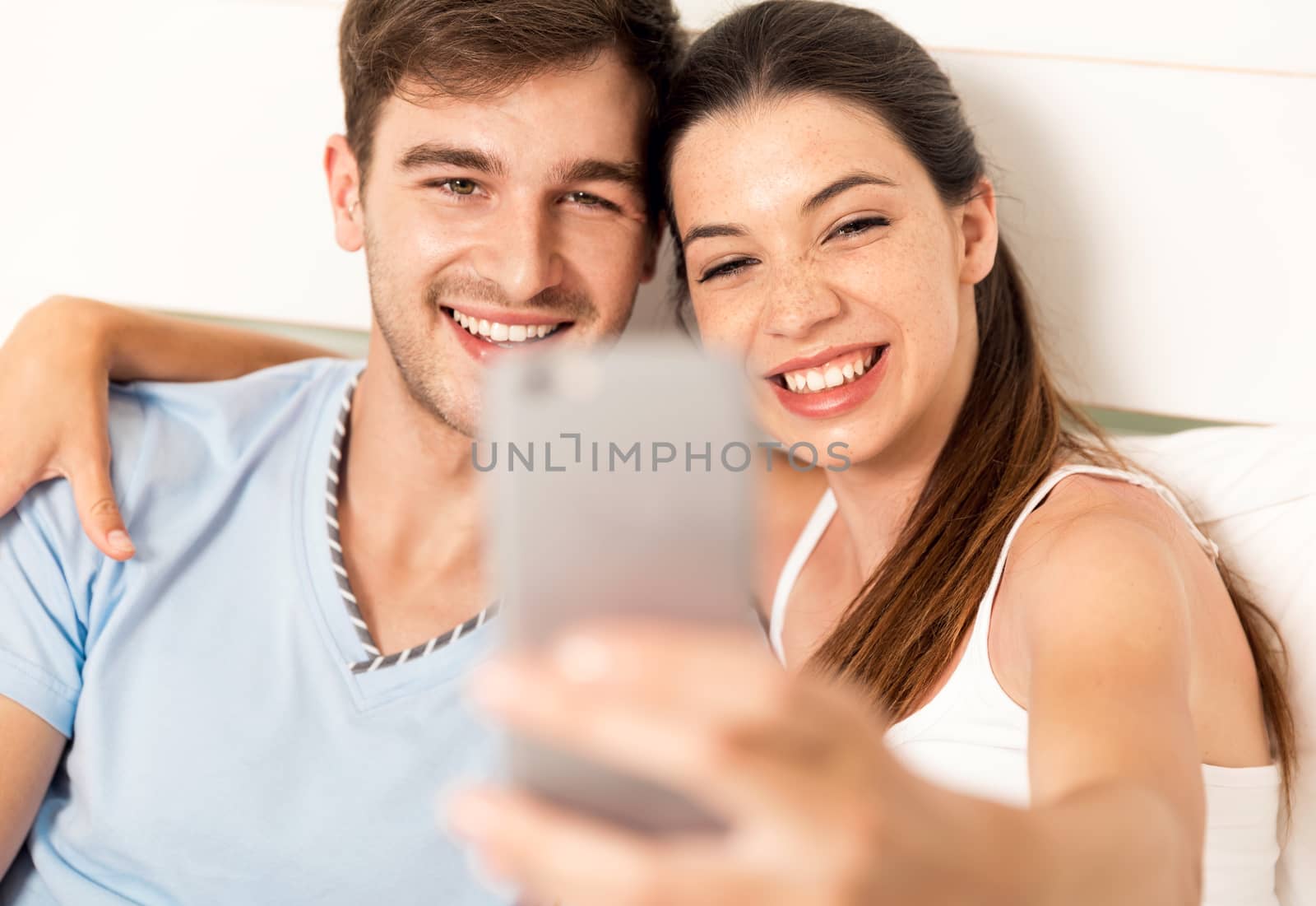 Young couple on bed making selfies with a phone