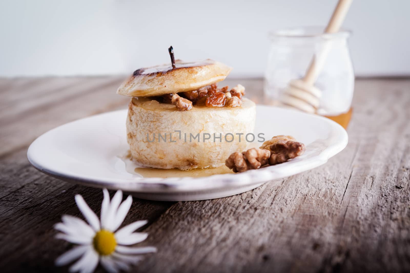 Baked apple with nuts and raisins on a wooden surface