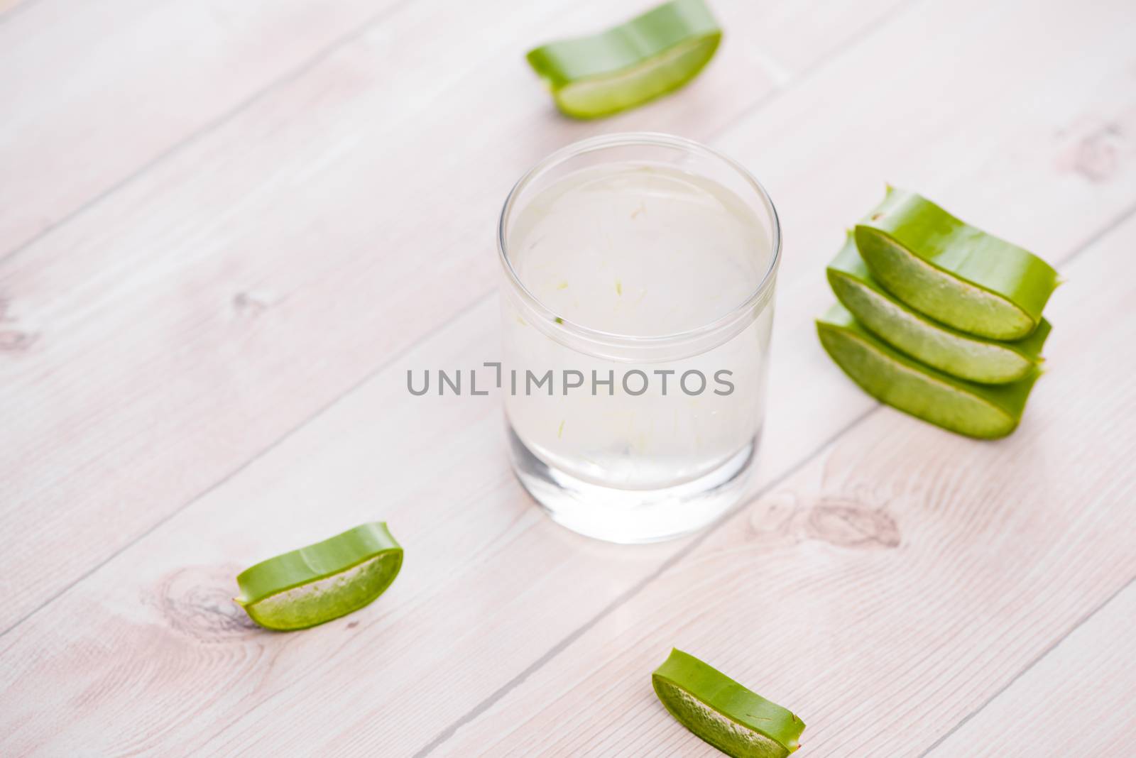 Glass of aloe vera juice with slices on a wooden table