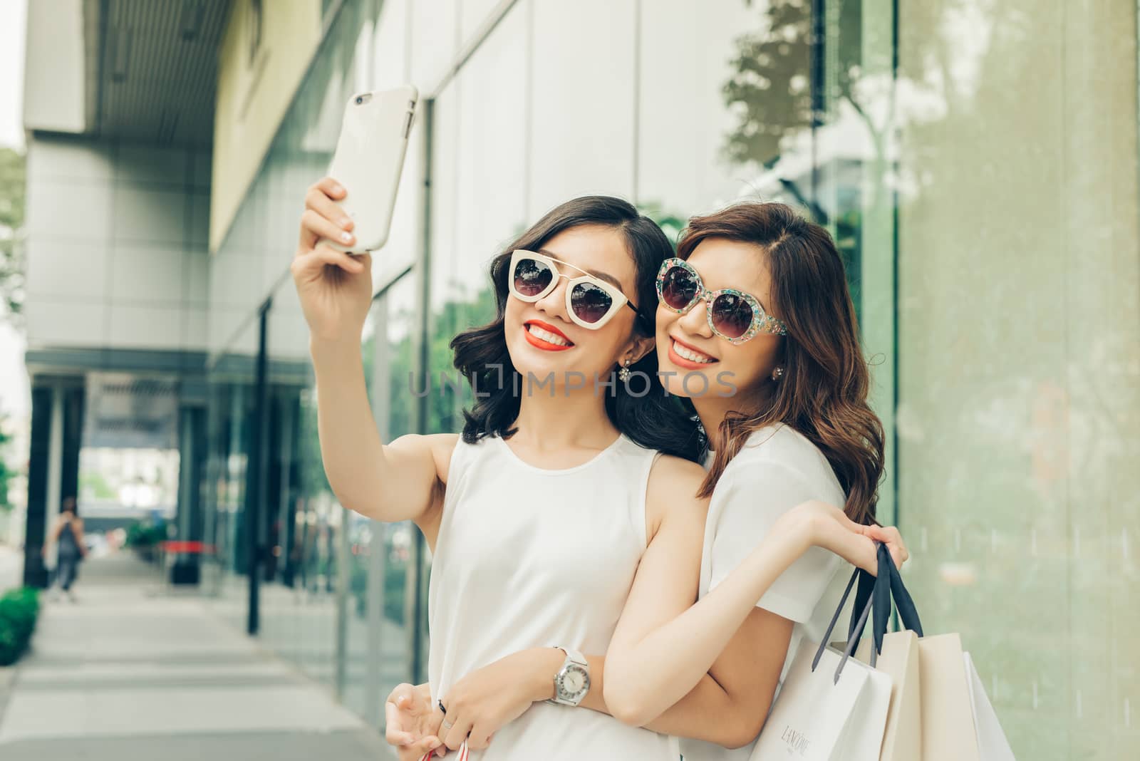 Beautiful asian girls with shopping bags taking selfie photo at the mall