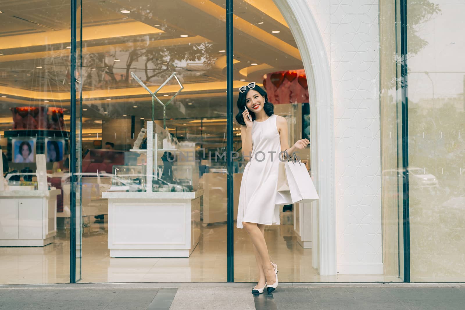 Beautiful asian girl with shopping bags listening to mobile phon by makidotvn