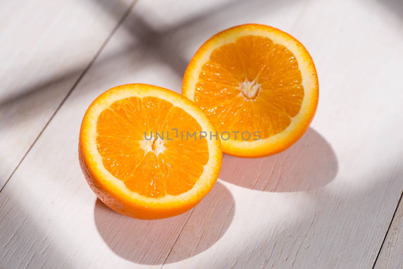 Half of orange on white wooden table.