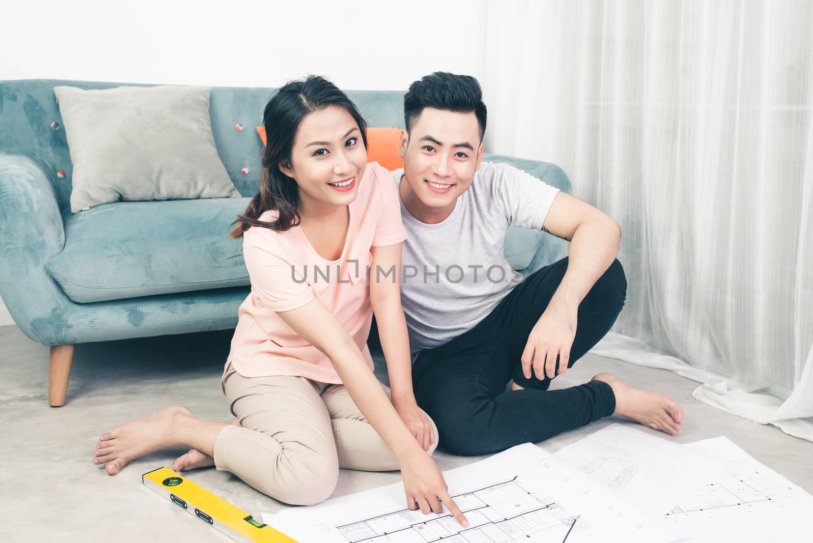 Attractive young asian adult couple looking at house plans.