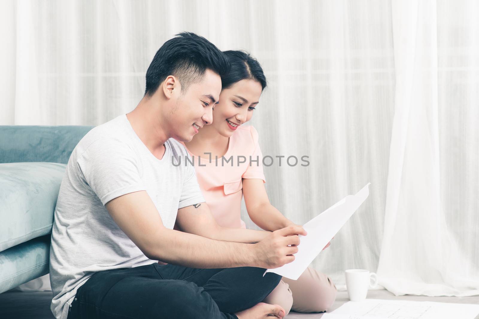 Attractive young asian adult couple looking at house plans. by makidotvn