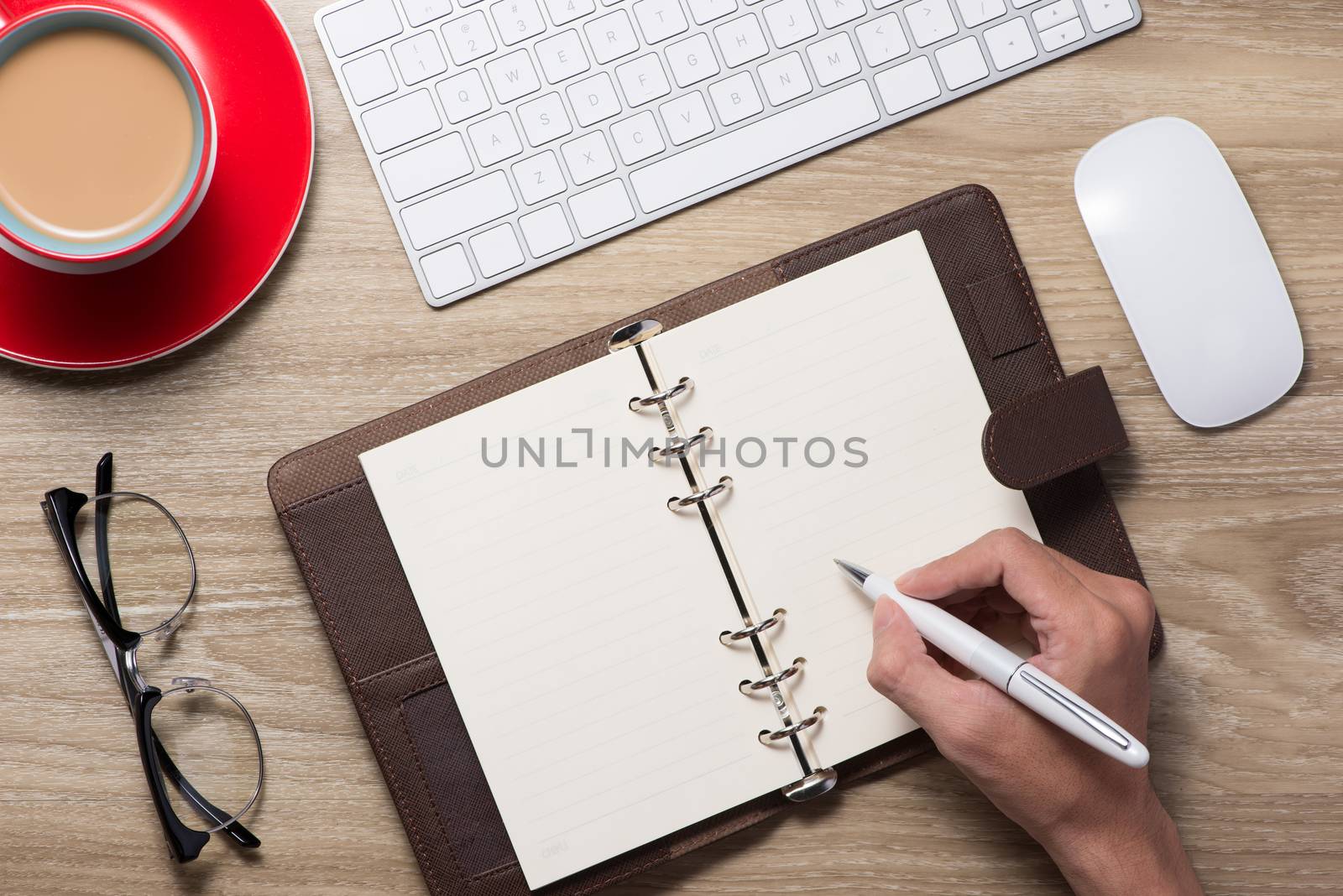 Blank white notebook open, eyeglass, pen and cup of coffee on the desk