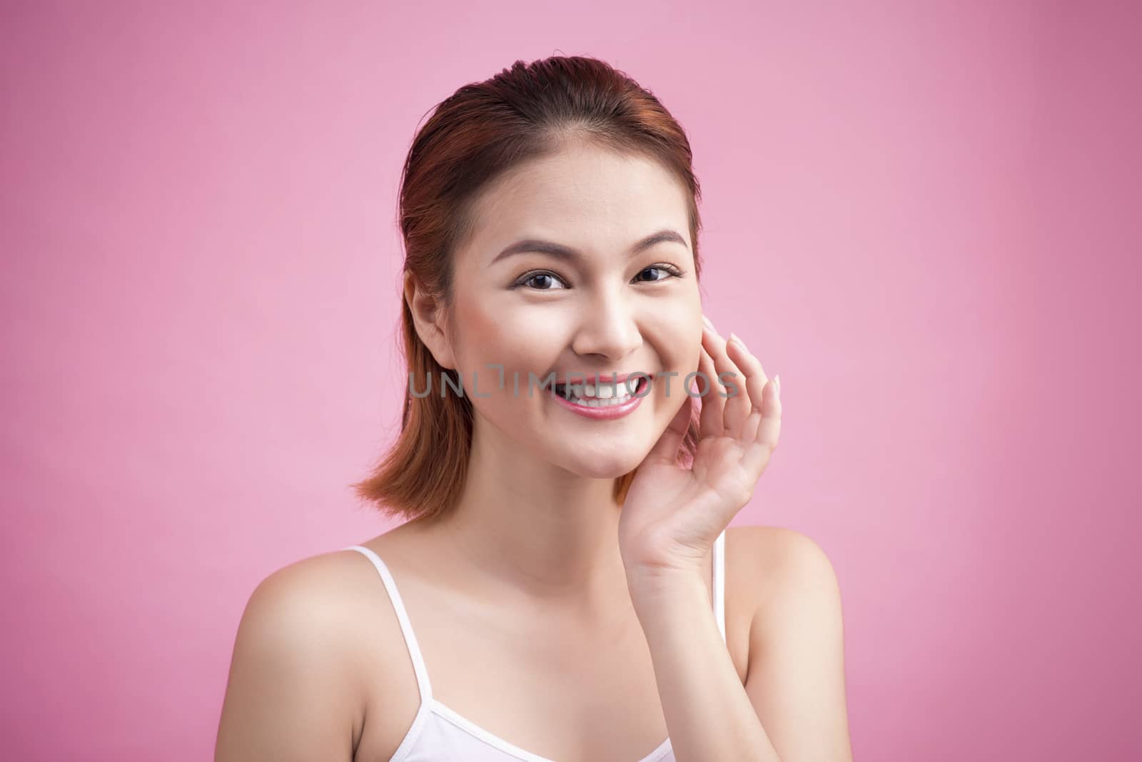 Portrait of a beautiful smiling young woman with natural make-up. Skincare, healthcare. Healthy teeth. Studio shot. Isolated on Pink Background.