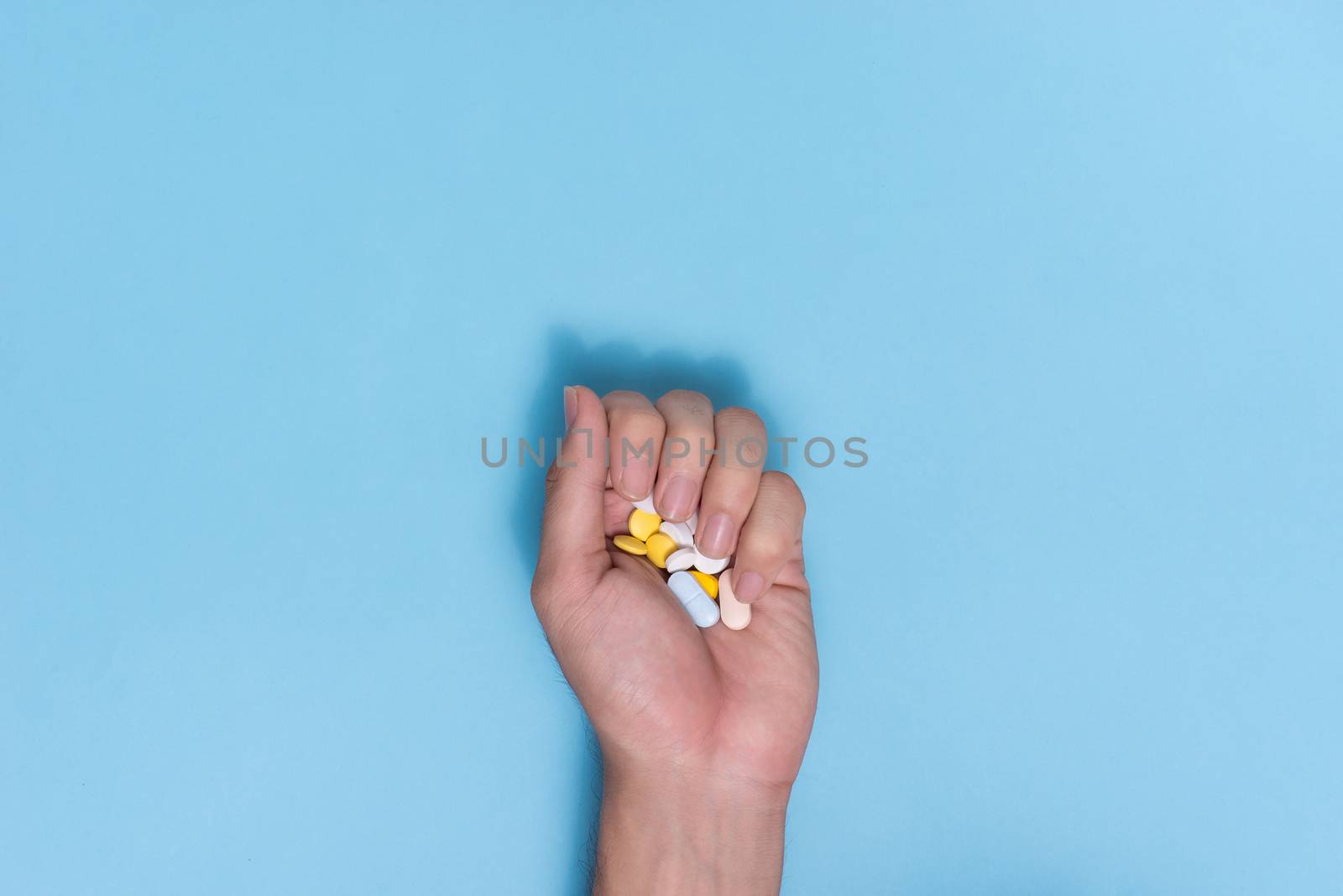 Colored pills in hand on blue background. by makidotvn
