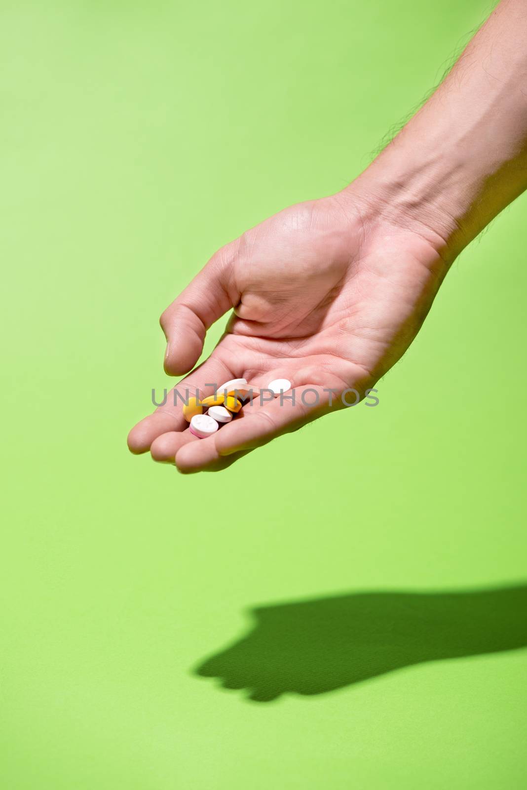 Colored pills in hand on green background. by makidotvn