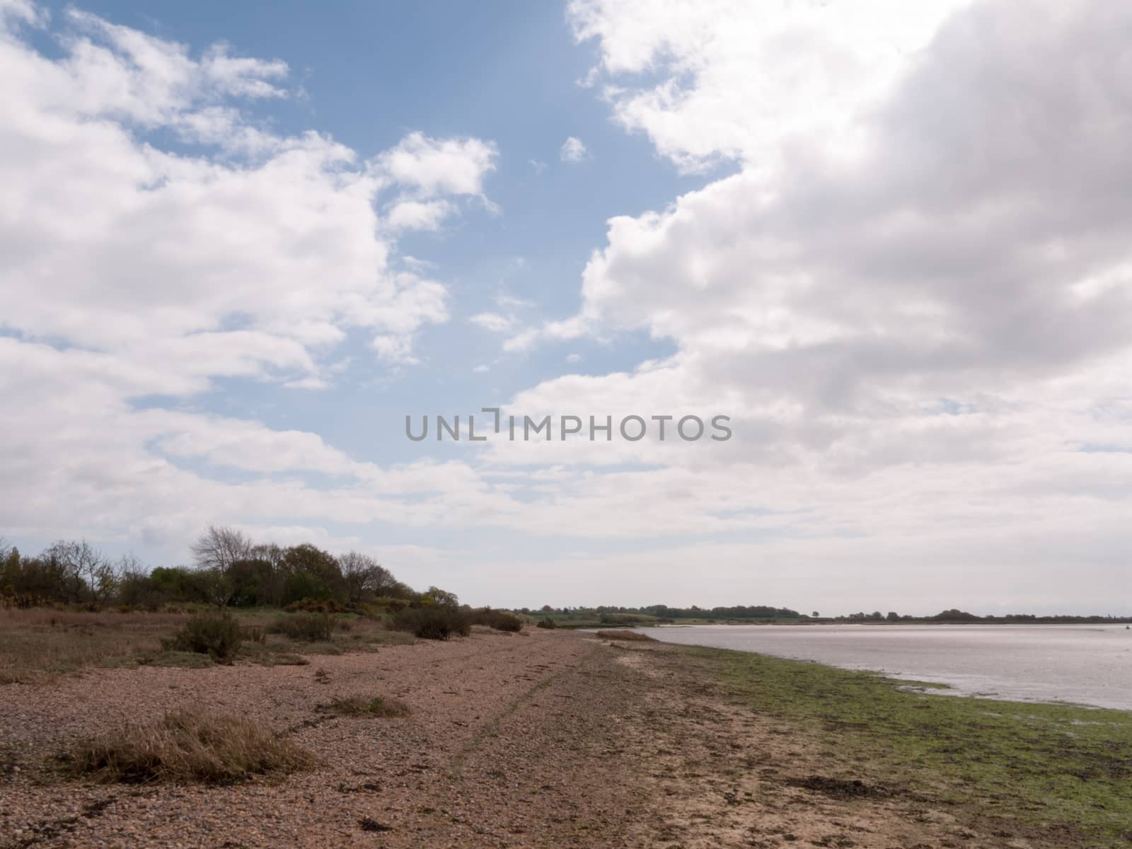 a landscape shot of the beach and sea with a cloudy blue sky and clear weather on a spring day