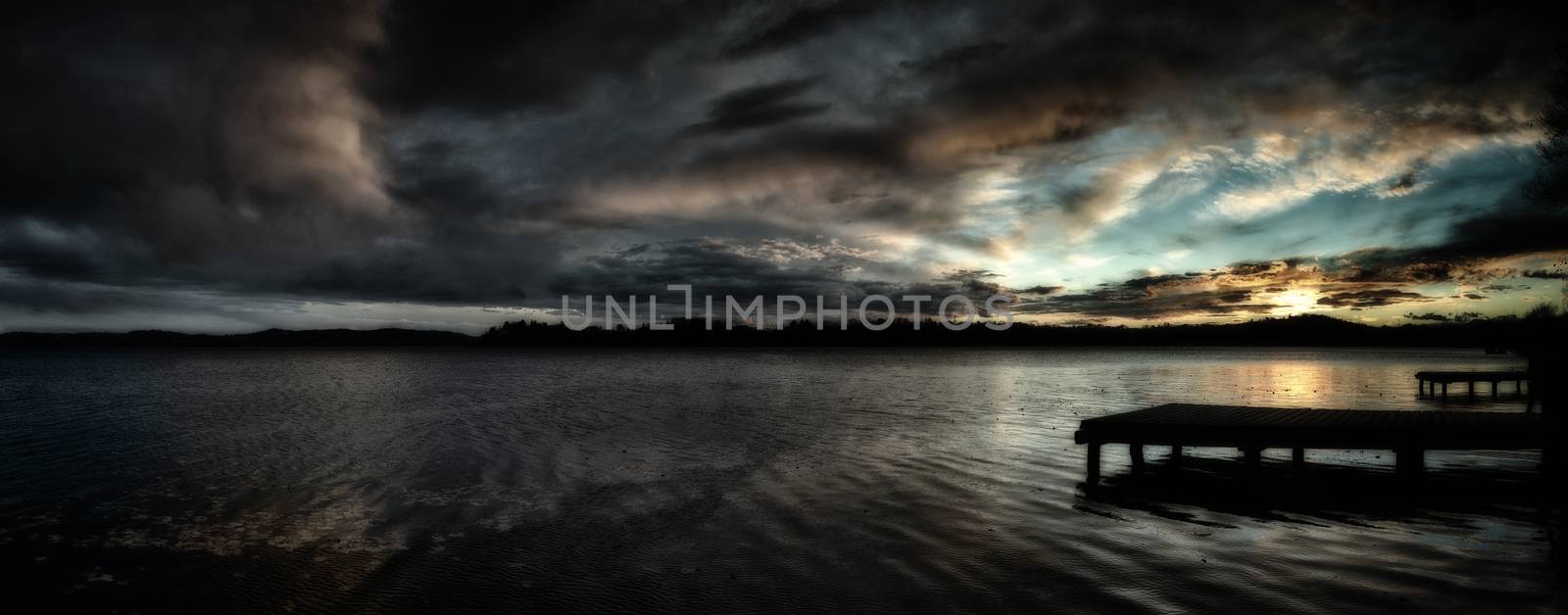 Sunset over the Lake of Varese with dramatic clouds and pier in the foreground