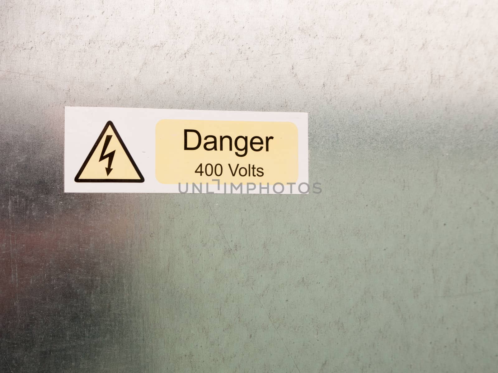 an electric bolt in triangle white yellow and black safety caution sign warning saying danger 400 volts attached to a metal wall background danger