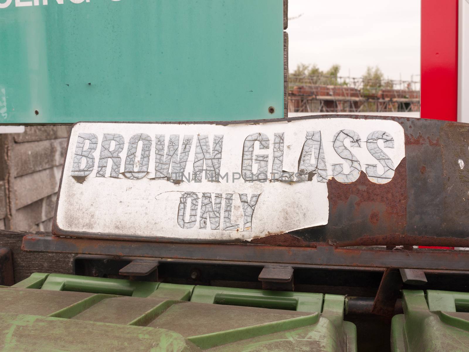 a sign saying brown glass only retro vintage worn faded tattered outside near recycling plant and green bins clean environment council england