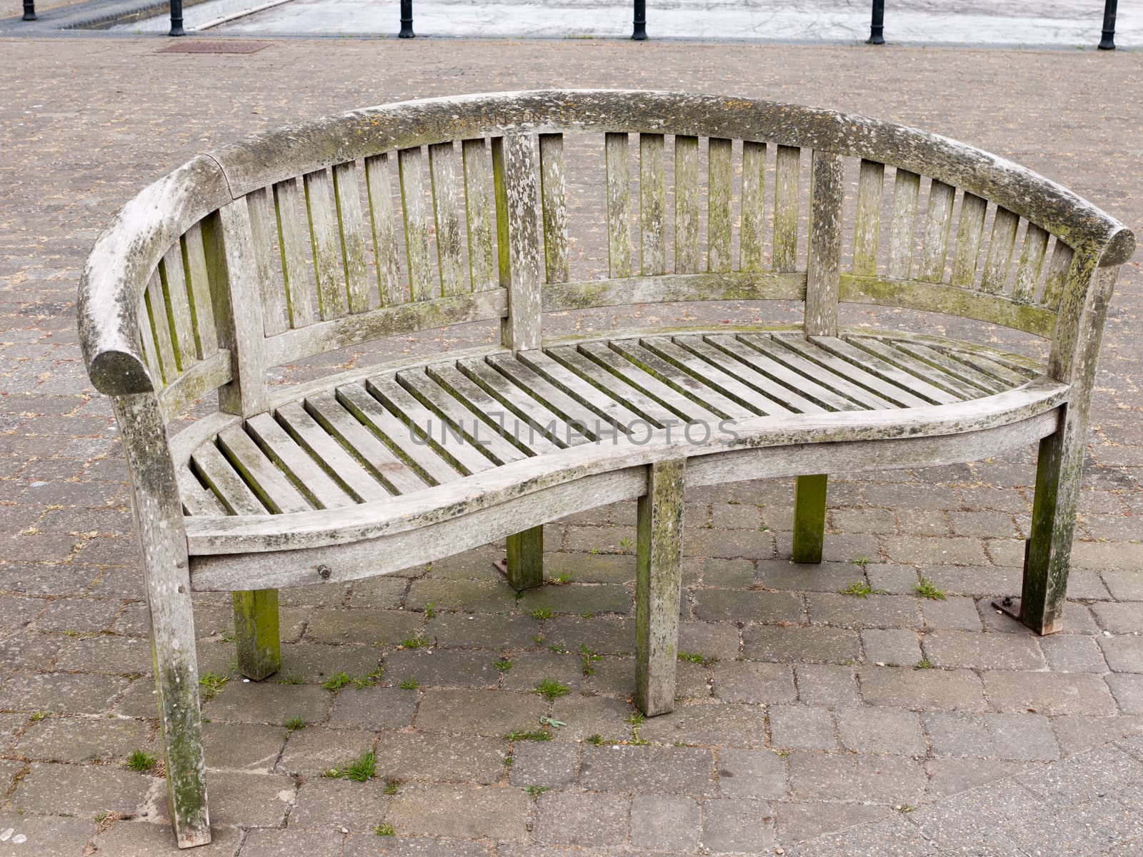 an empty wood bench outside on the pavement bricks with moss and by callumrc