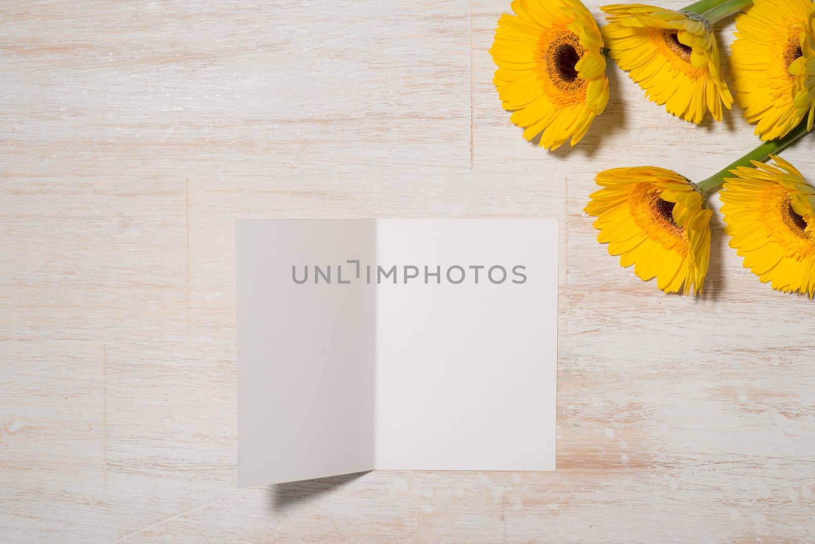 Greeting card with yellow flowers over wooden background. Top view with copy space