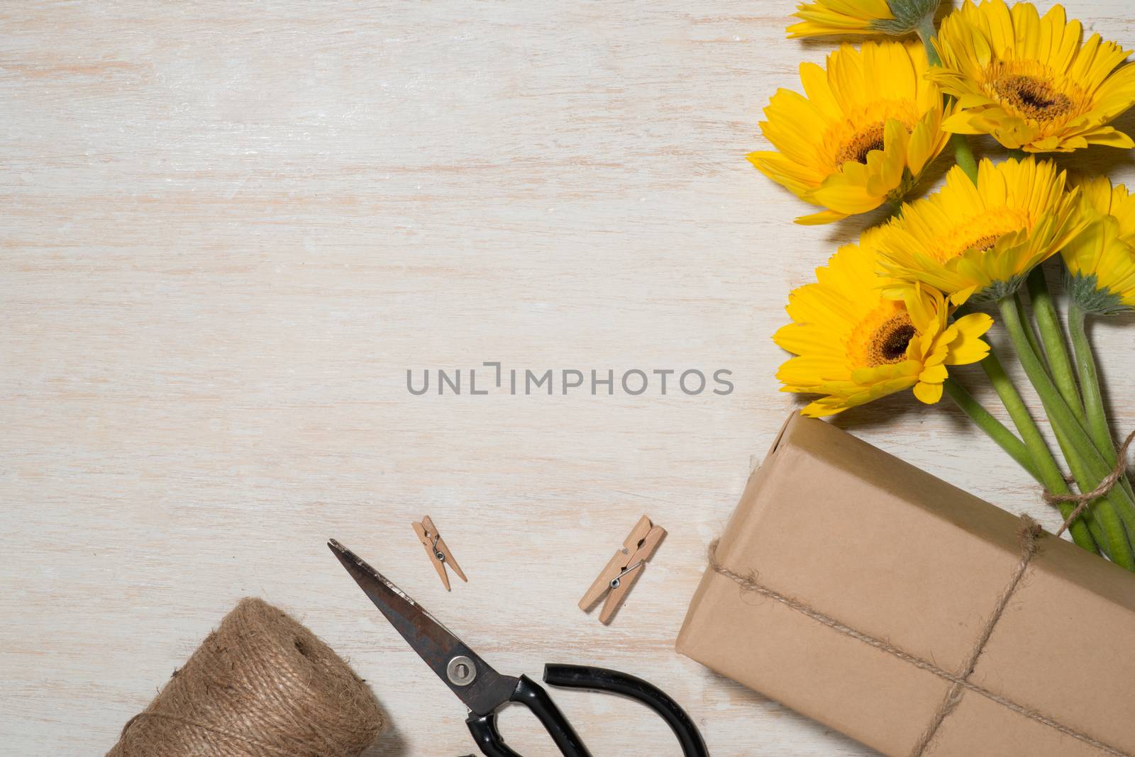 Wrapping flowers gift over wooden background. Top view with copy space