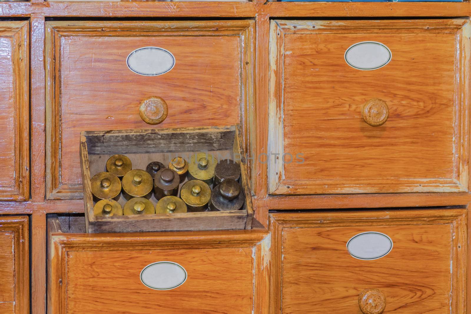 Close up of a very old pharmacy medicine drawer cabinet with small brass weights