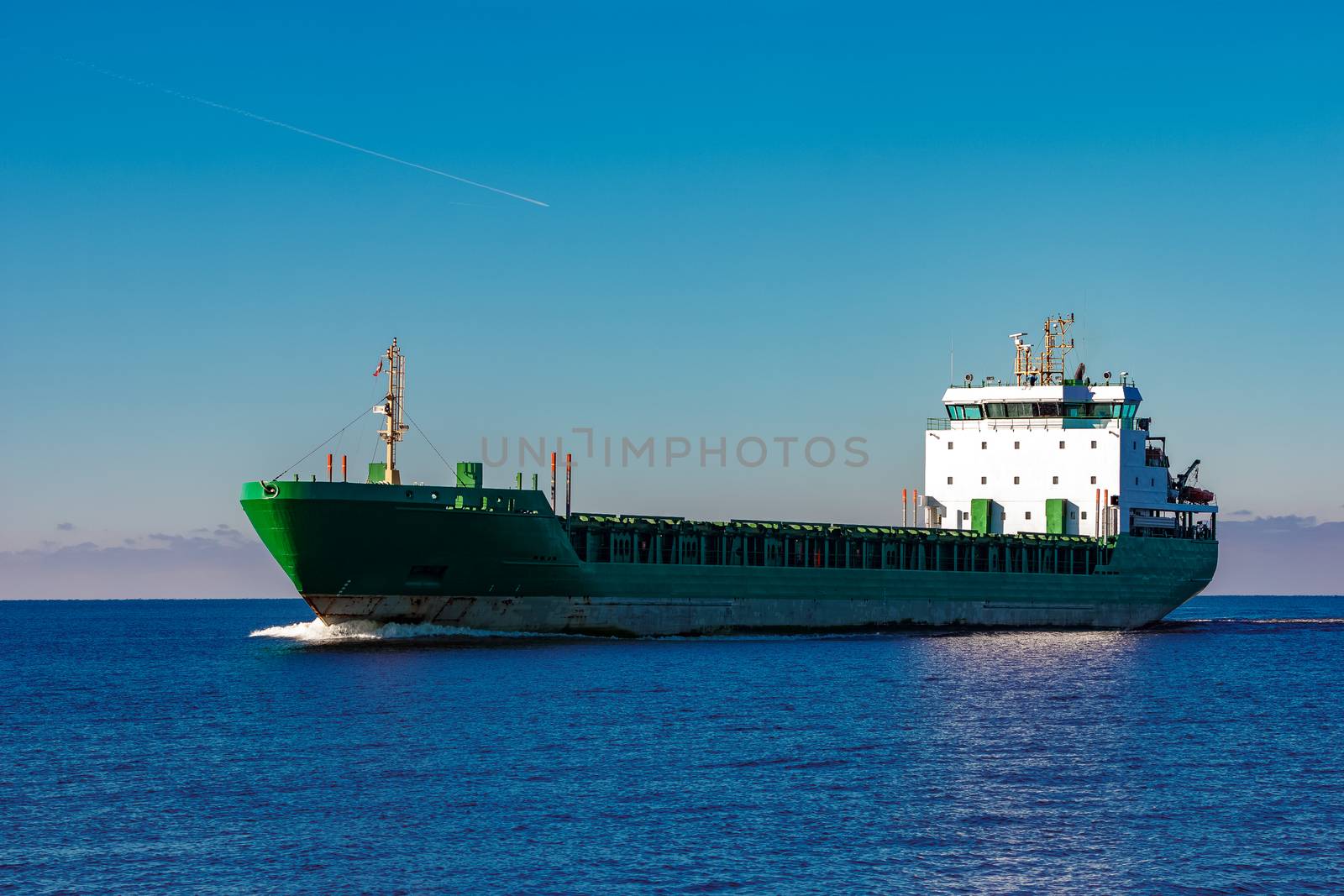 Green cargo ship moving in still water of Baltic sea