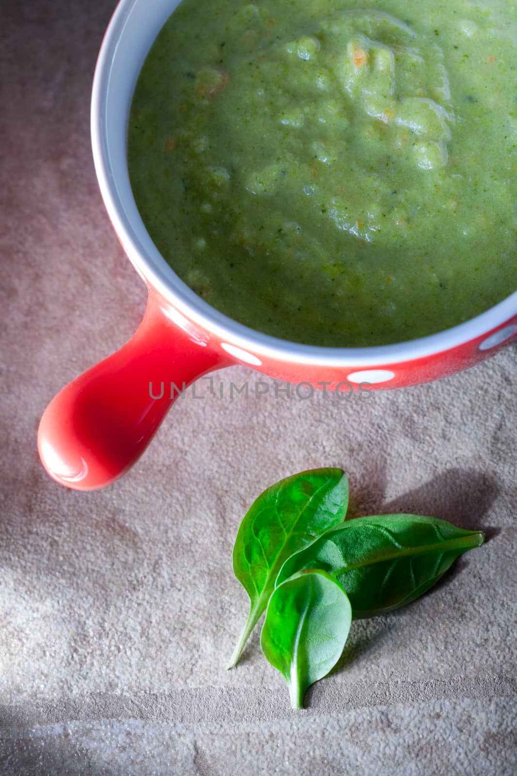 Spinach cream soup with greenery on a stone surface