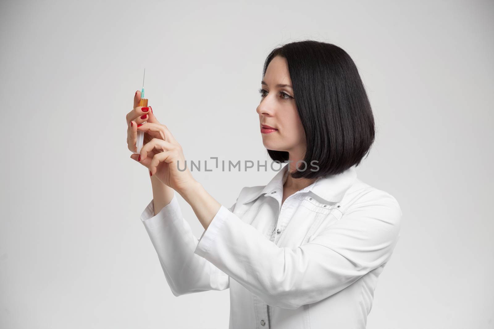 the beautiful woman the doctor with the syringe on a white background