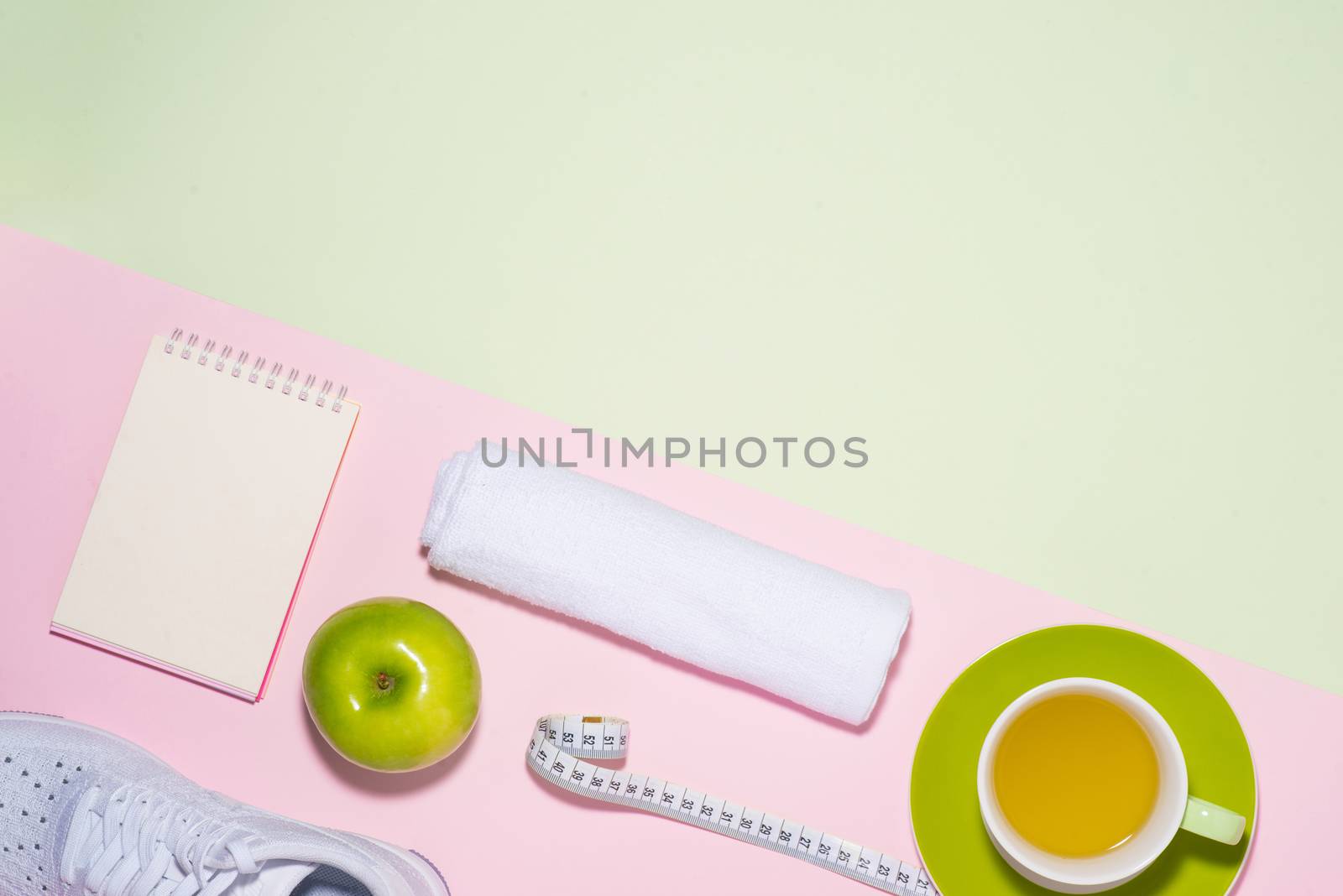 Healthy concept. Sneakers, tea, apple and measure tape on pastel color background.