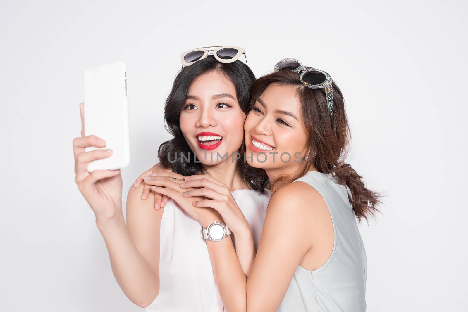 Portrait of two beautiful asian fashionable women taking selfie by makidotvn