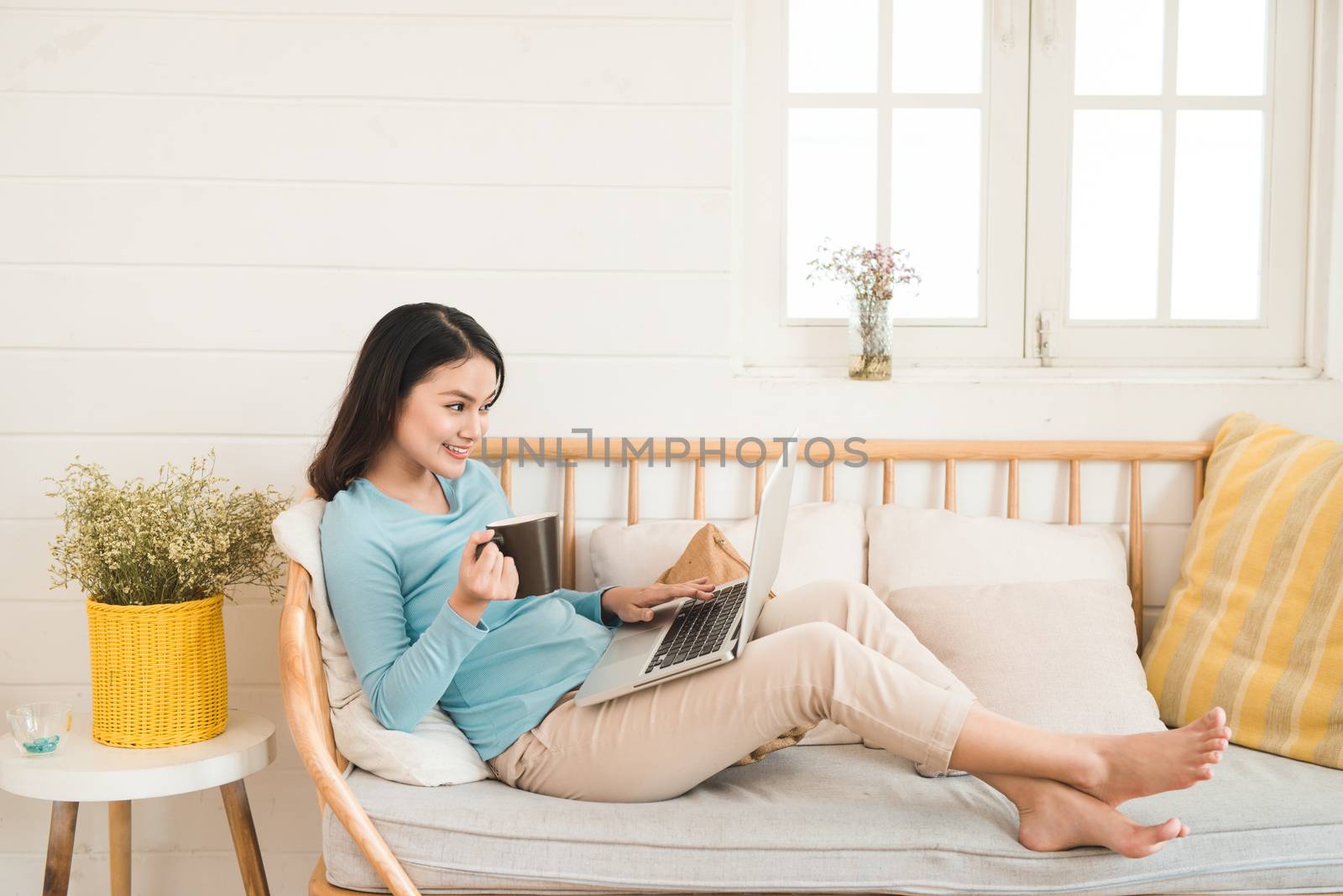 Happy casual beautiful asian young woman working on a laptop at  by makidotvn