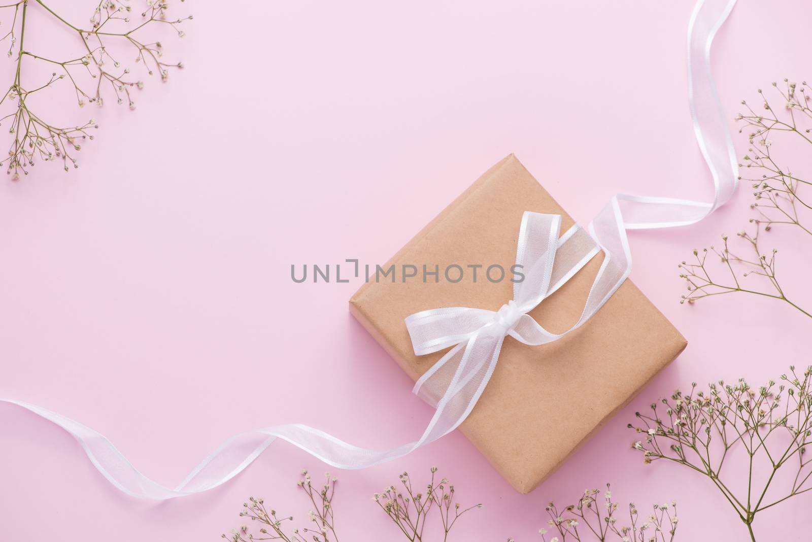 Kraft paper gift box tied with pink ribbon and white flowers for mothers day