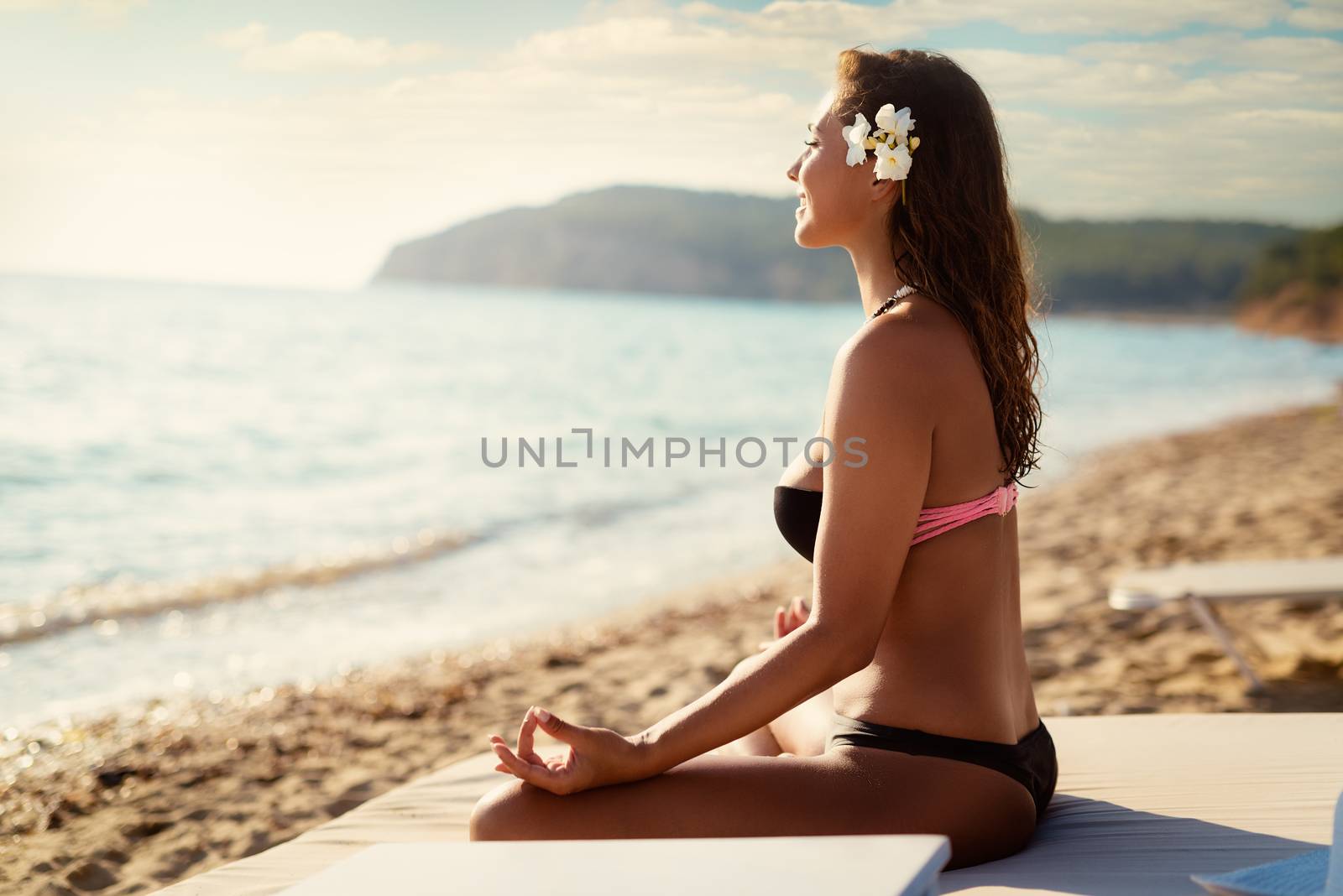 Beautiful young woman doing yoga on the beach.