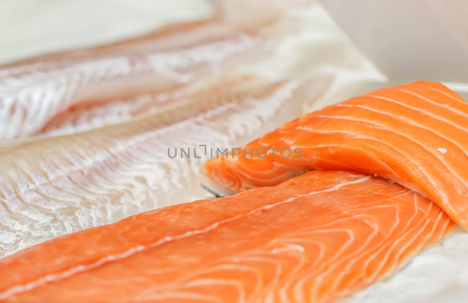 fresh uncooked salmon fillet on showcase of seafood market. by pixinoo