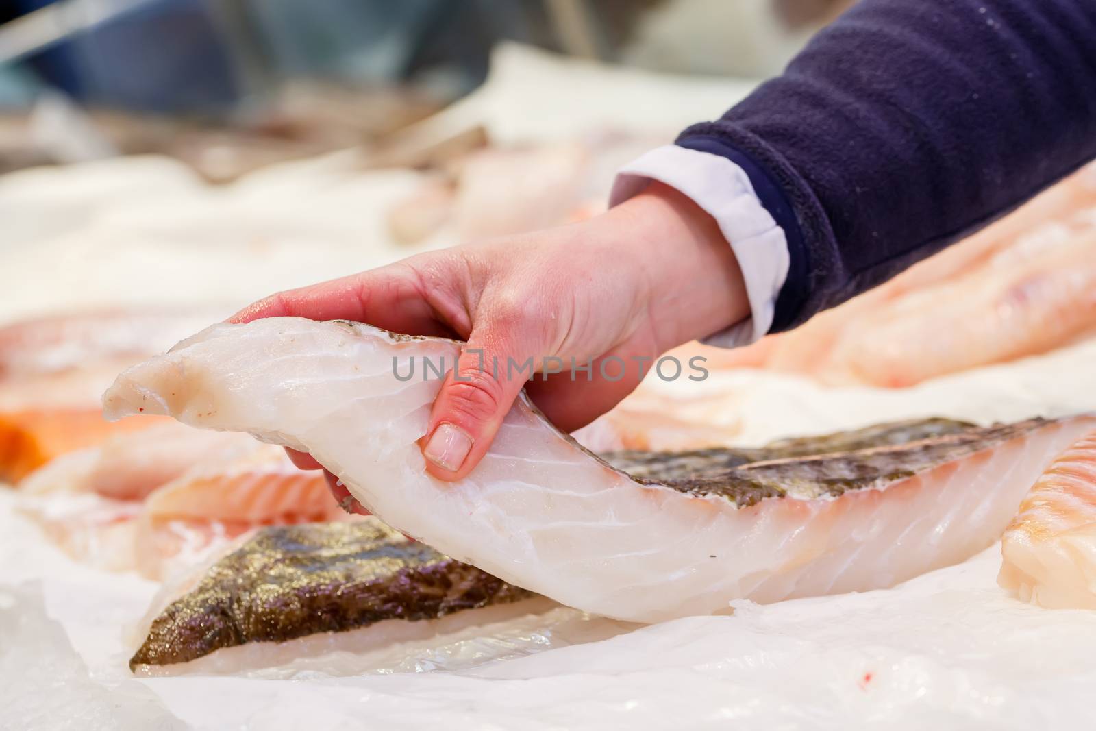 Fishmonger holding a piece of fresh fish in a market by pixinoo