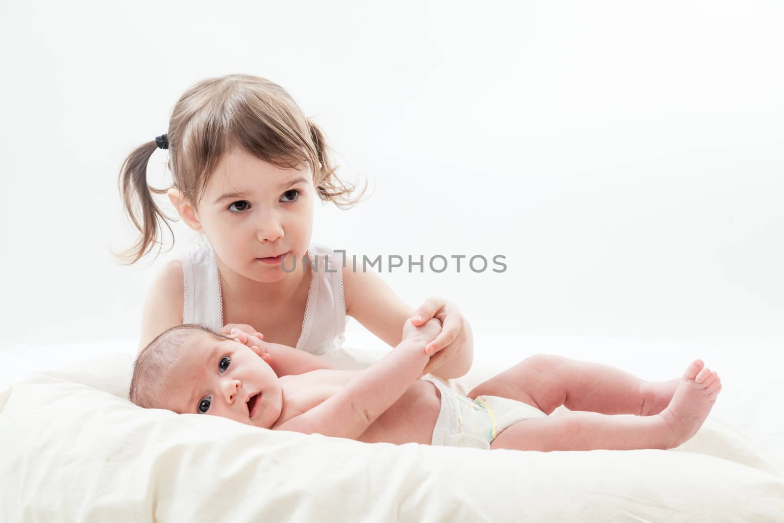 elder sister and the younger newborn child on a white background