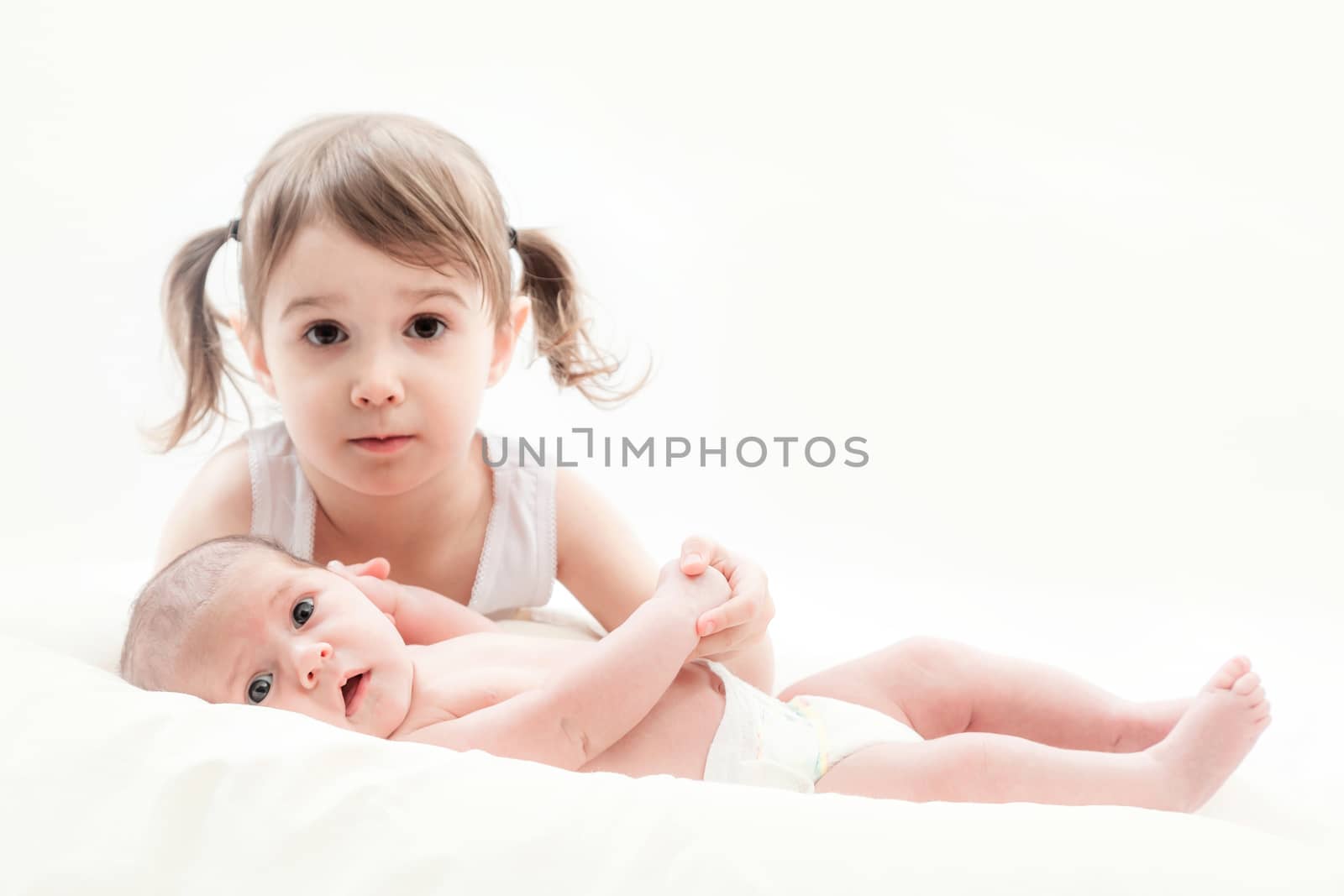 elder sister and the younger newborn child on a white background