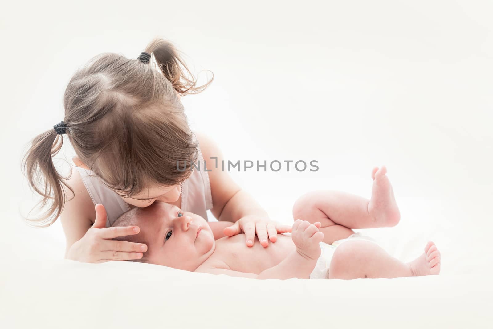 elder sister and the younger newborn child on a white background