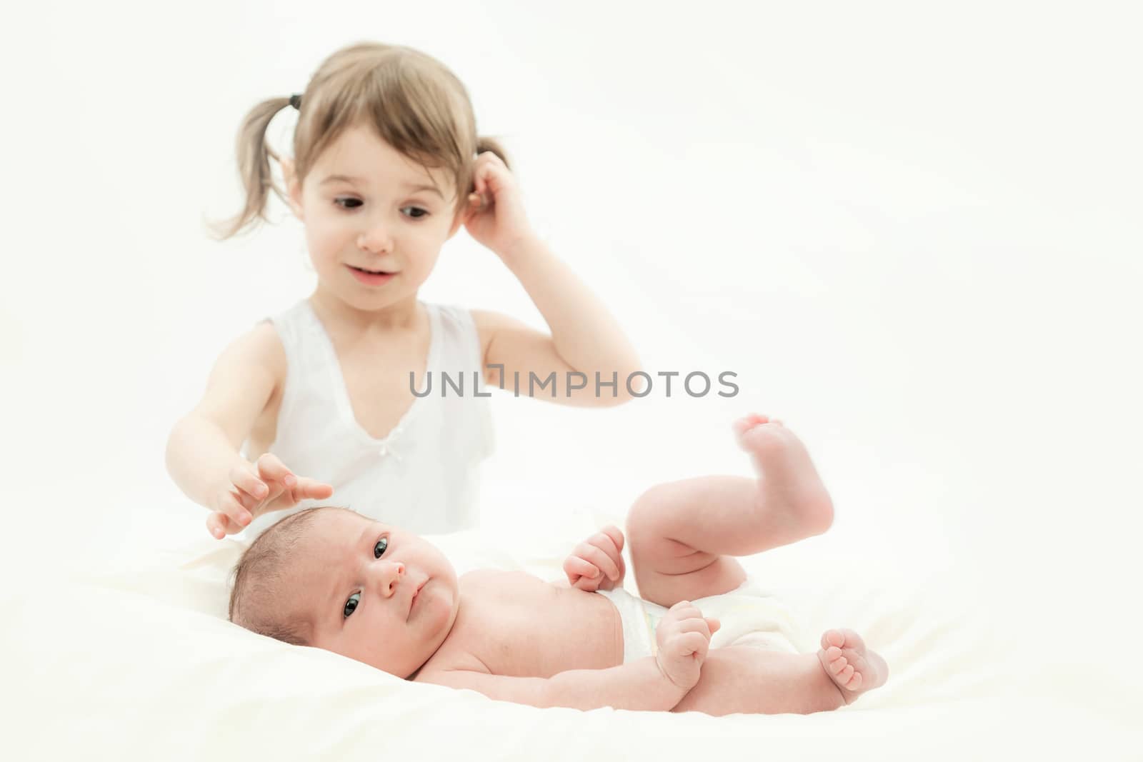 elder sister and the younger newborn child on a white background