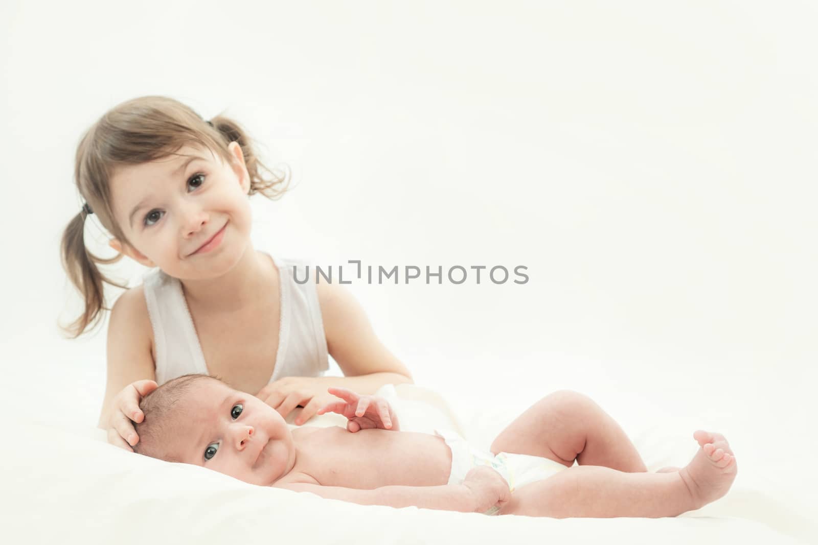 elder sister and the younger newborn child on a white background