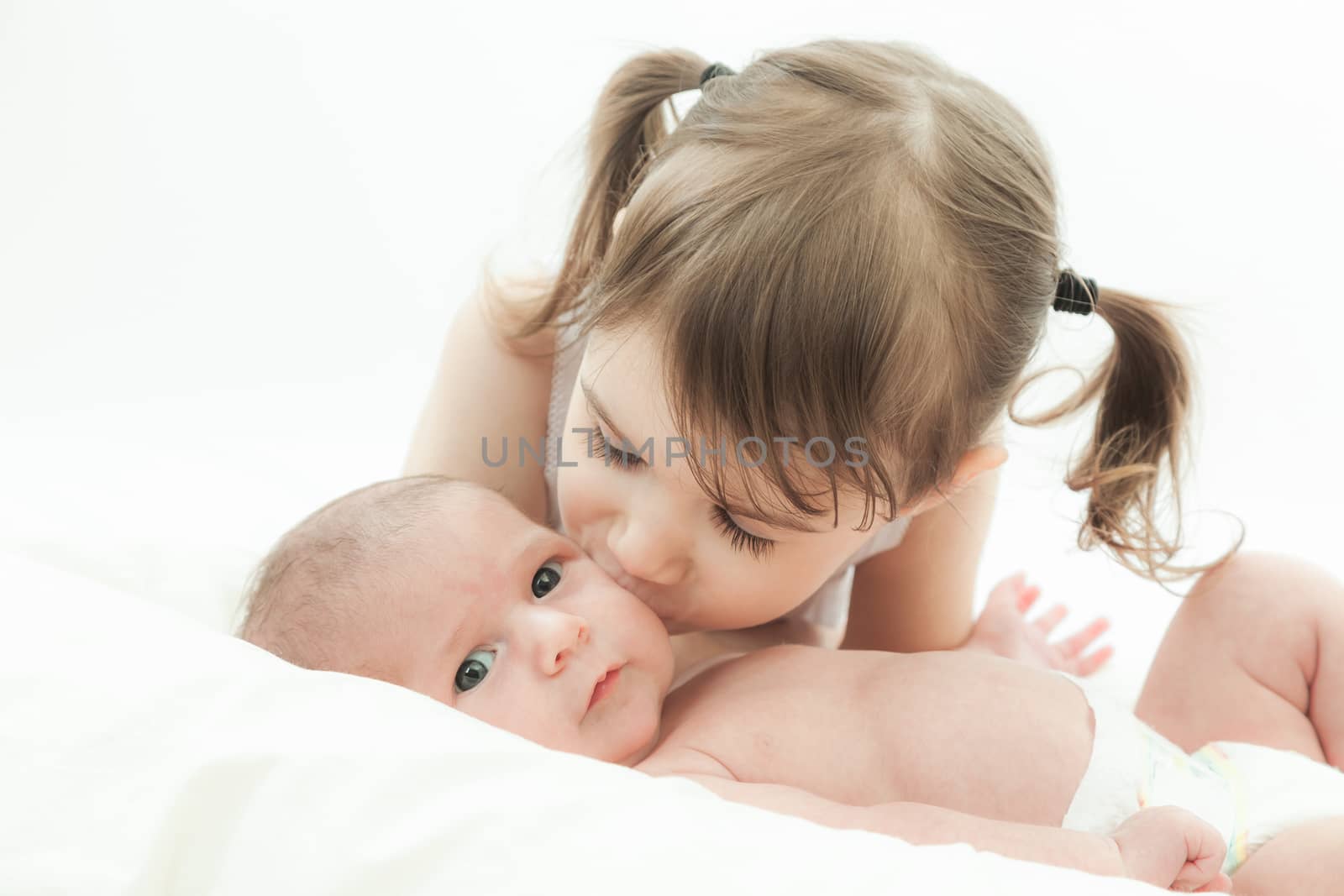 elder sister and the younger newborn child on a white background