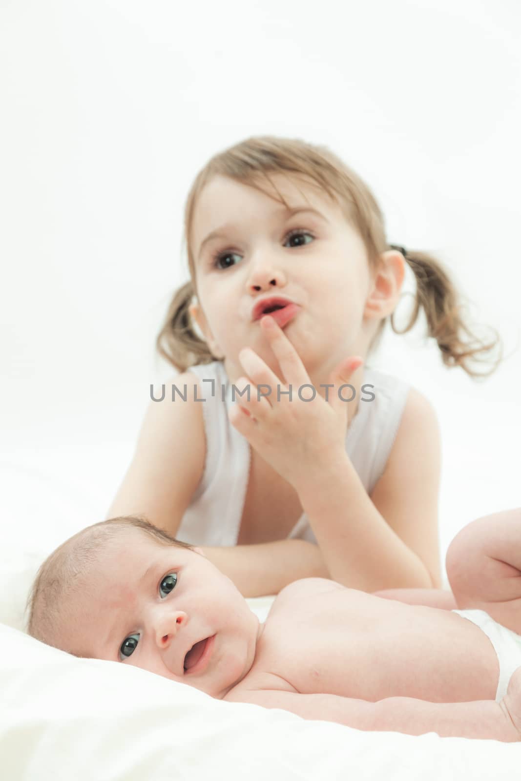 elder sister and the younger newborn child on a white background