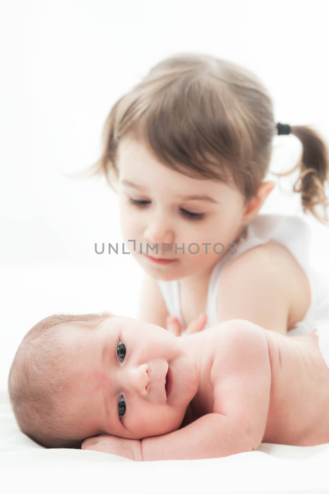 elder sister and the younger newborn child on a white background