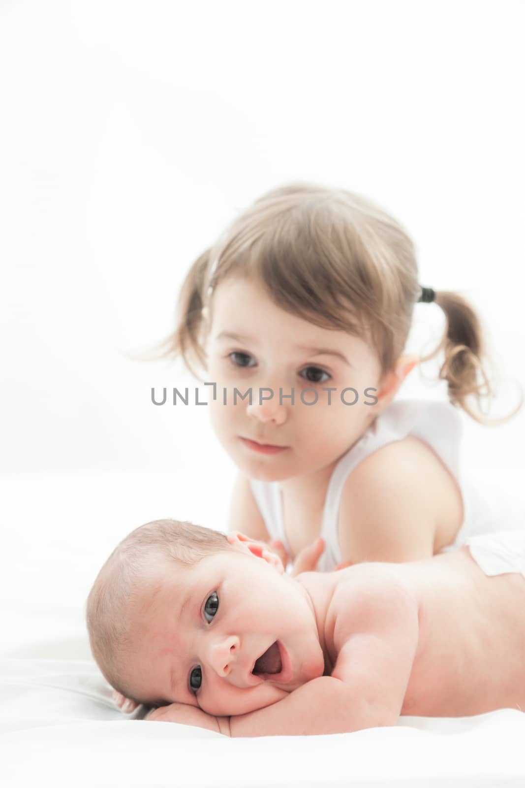 elder sister and the younger newborn child on a white background