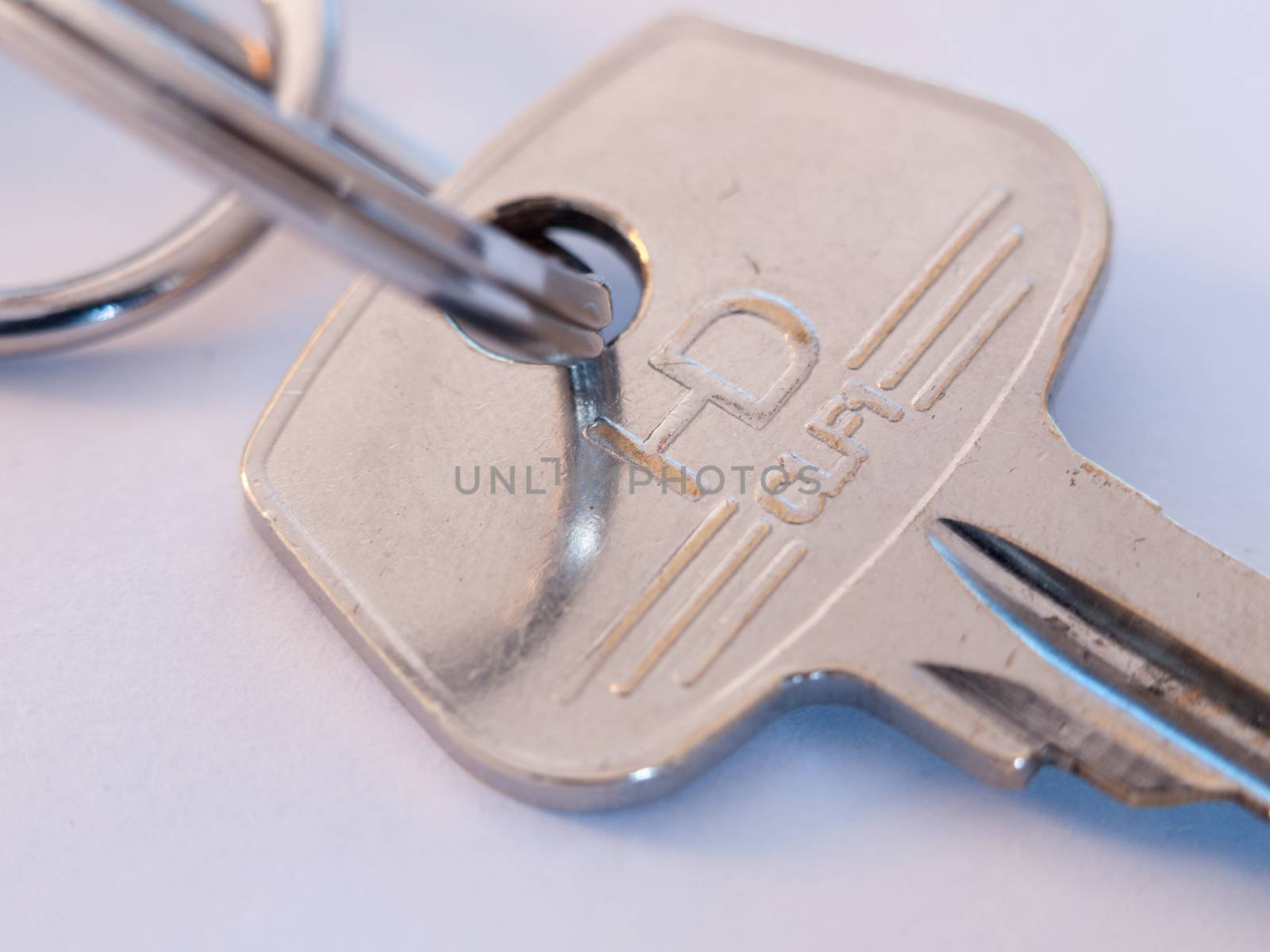 close up top part of metal steel single key and keyring macro on white background