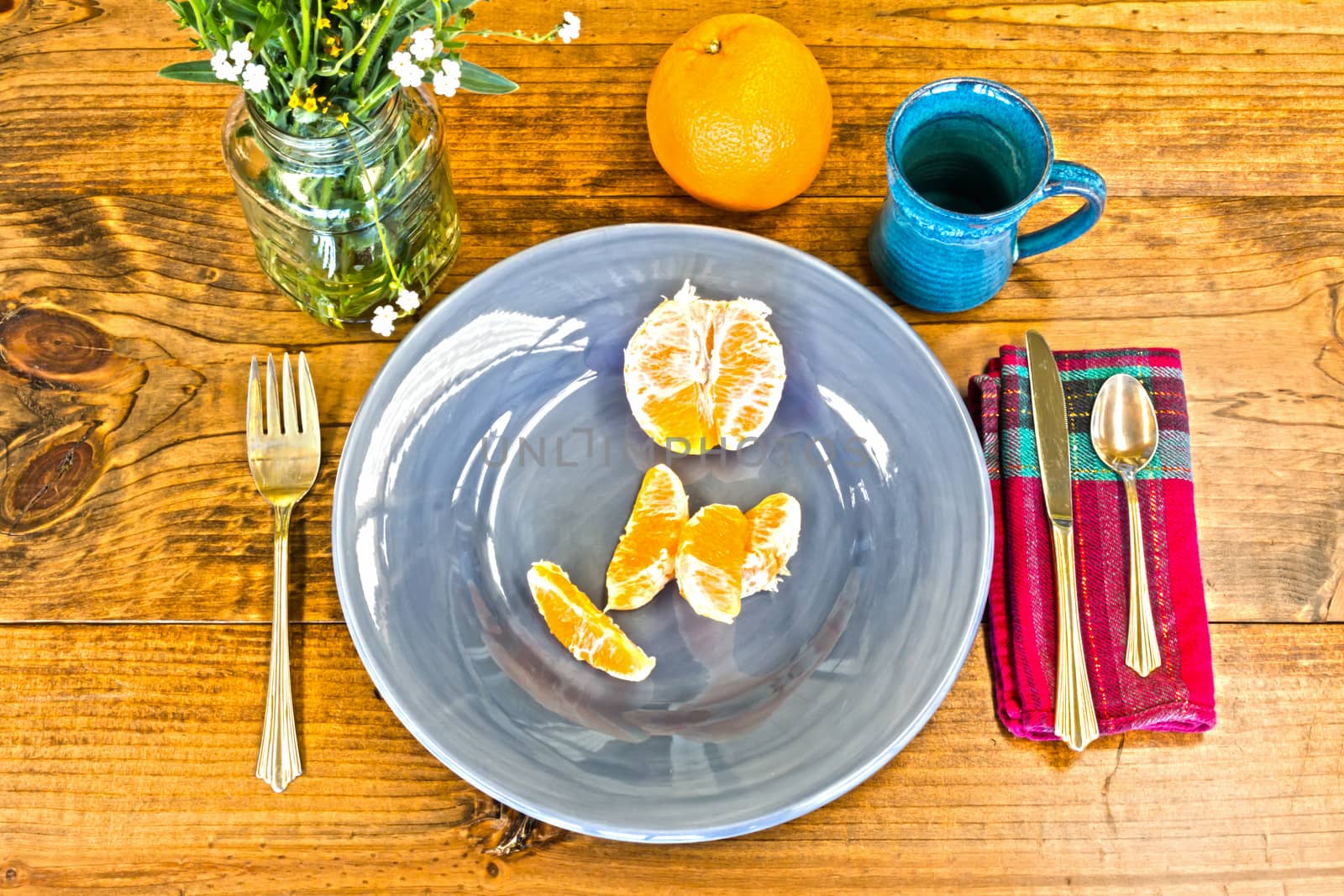 Place Setting With Orange Peels and Blue Cup on Wooden Table With Knots