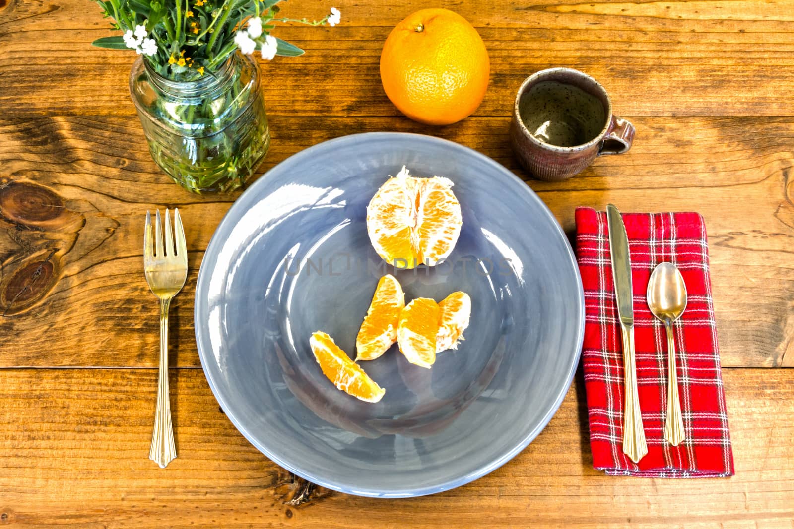Place Setting With Orange Peels and Brown Cup on Wooden Table With Knots