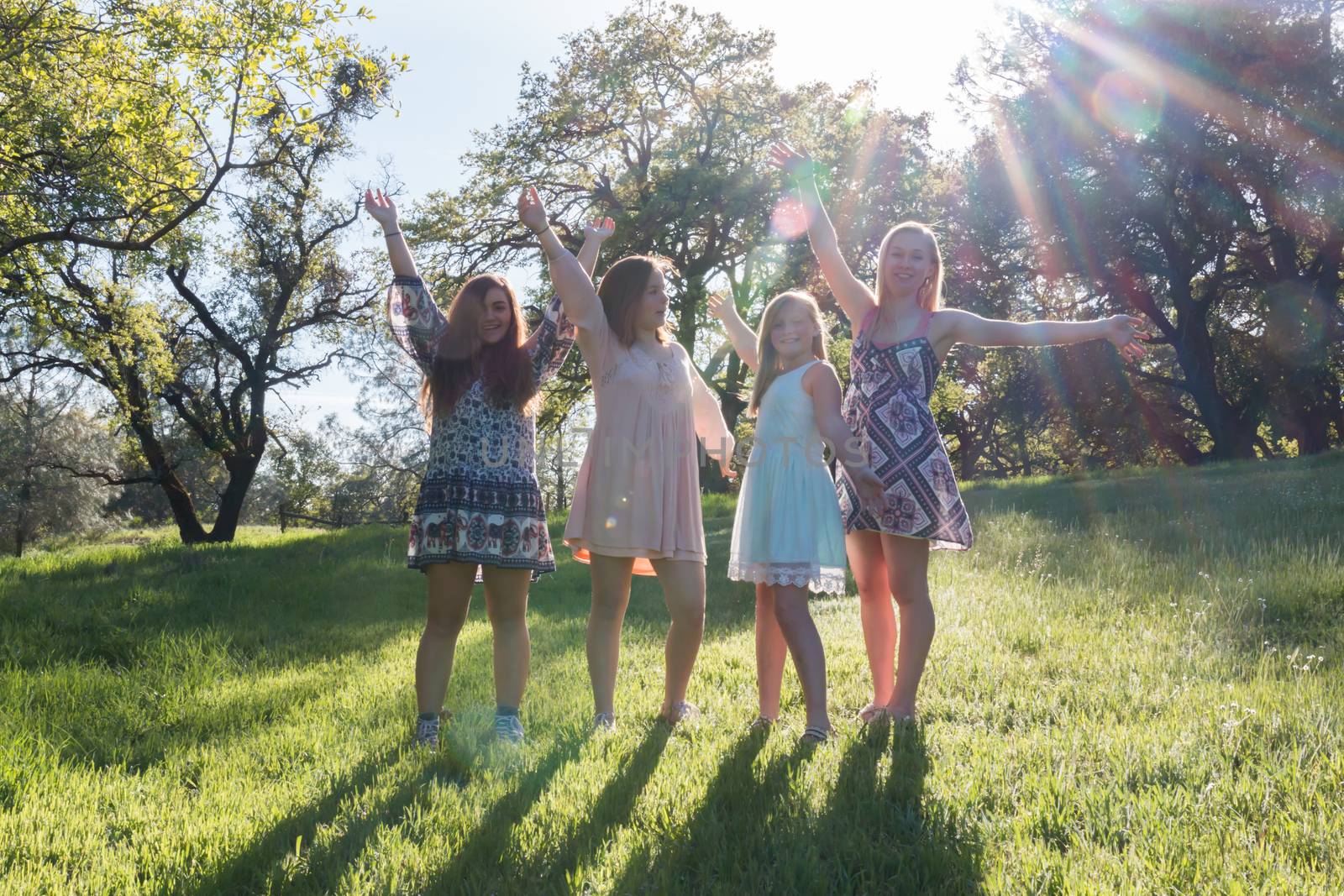 Group of Girls Standing With Arms Raised and Sunlight Overhead