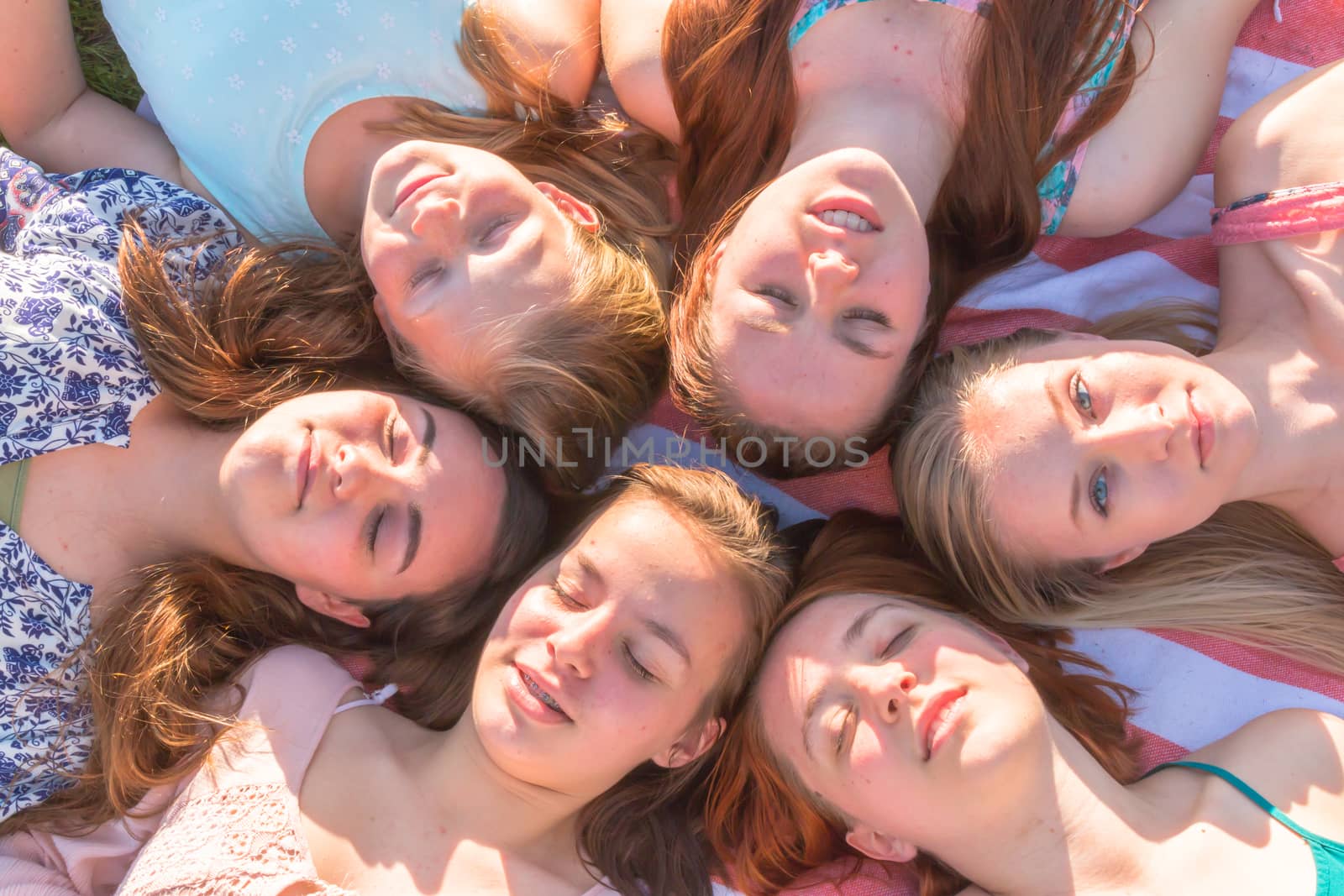 Young Girls Laying on the Ground Smiling and Looking up, Some With Eyes Closed