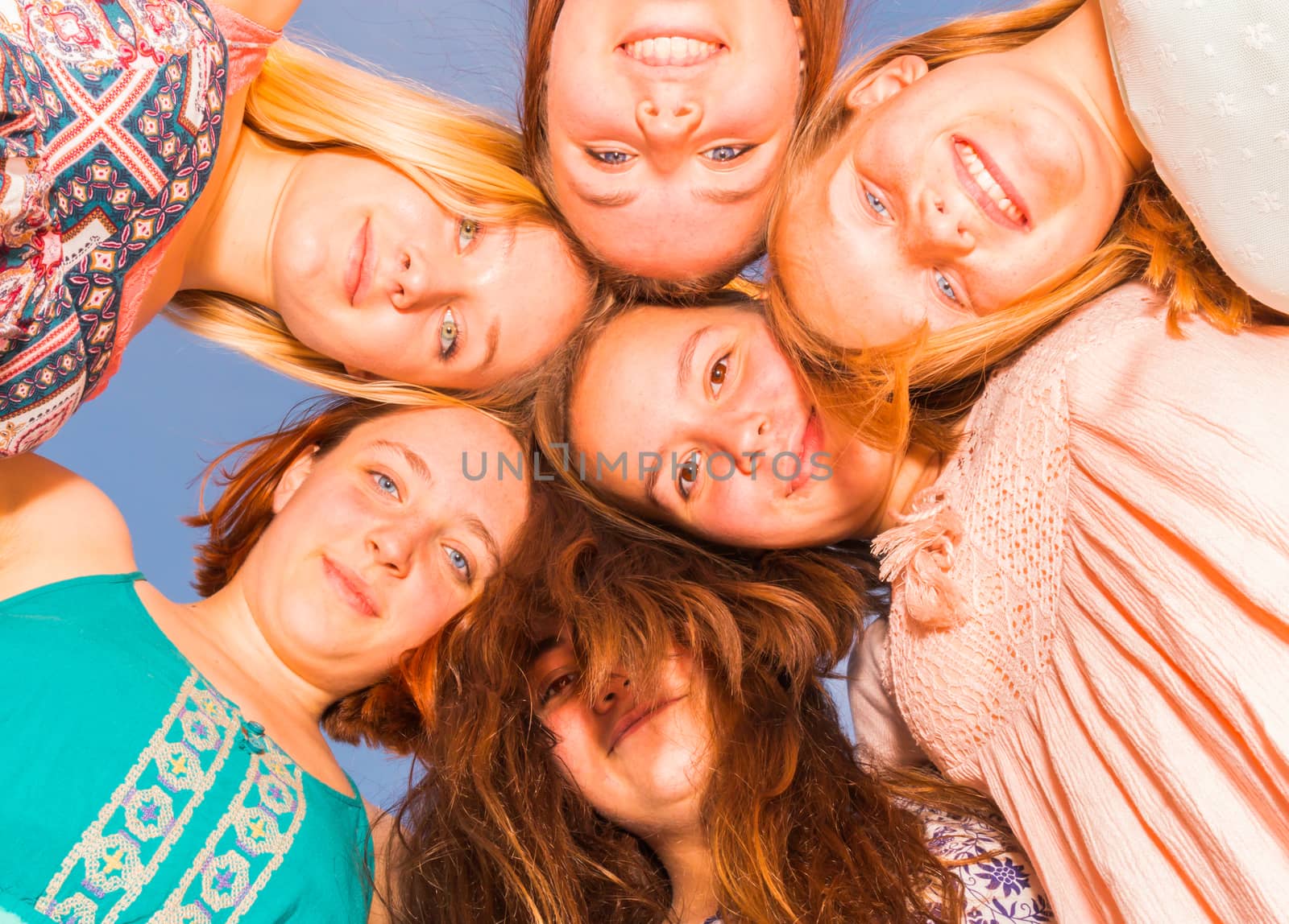 Young Girls With Heads Together Looking Down With Blue Sky in the Bakground