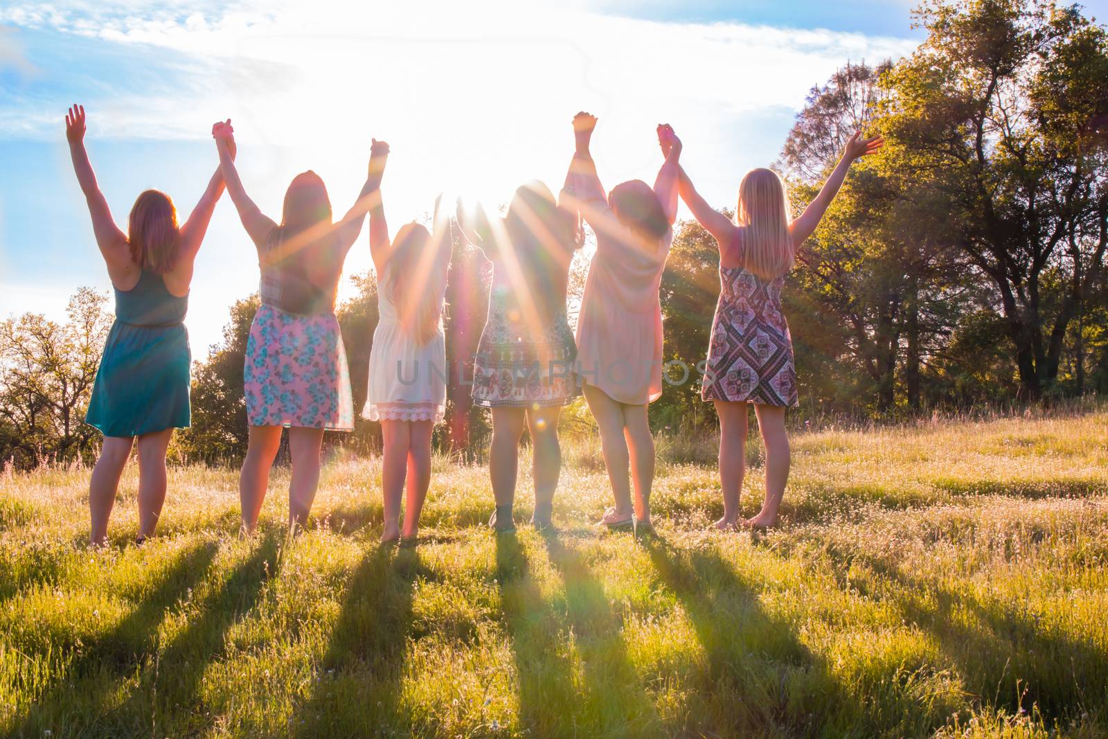 Group of Girls Standing With Arms Raised and Sunlight Overhead