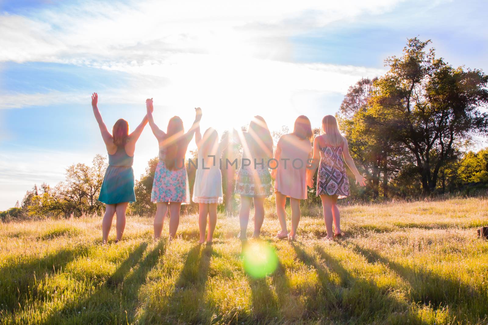 Group of Girls Standing With Arms Raised and Sunlight Overhead