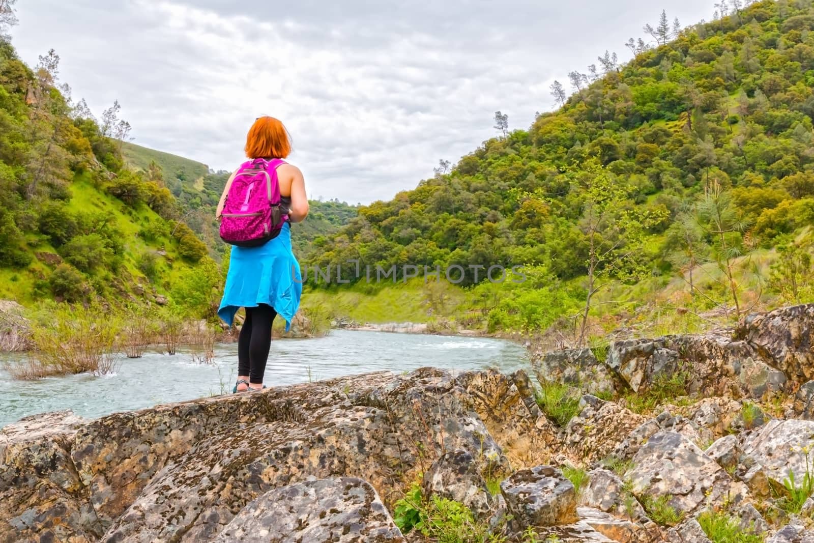 Young Girl Standing on Rocks Near Fast River