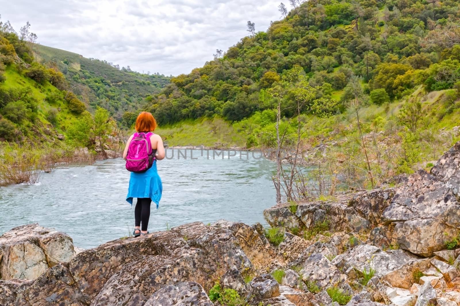 Young Girl Standing on Rocks Near Fast River