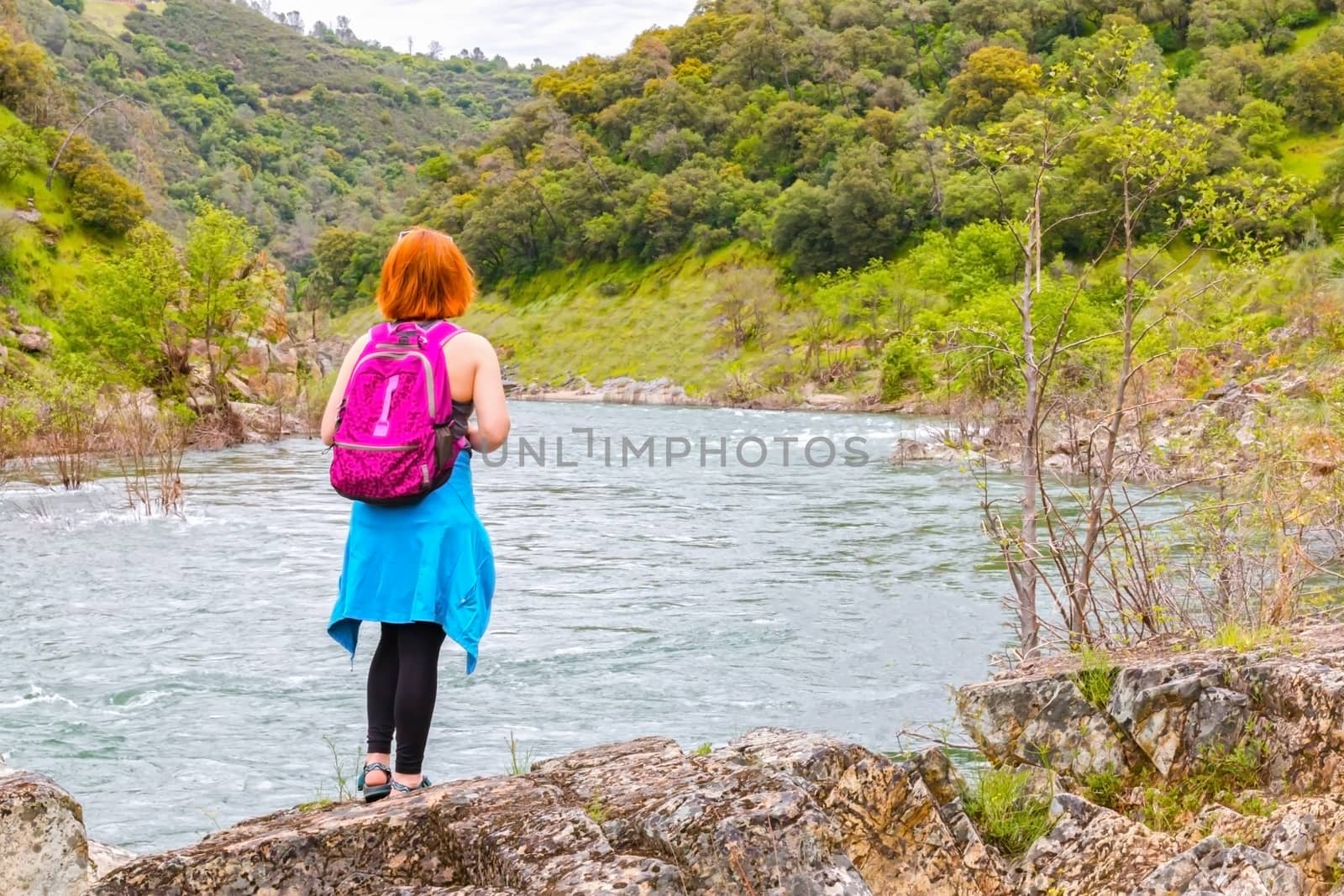 Girl Standing on Rocks Near Fast River by gregorydean